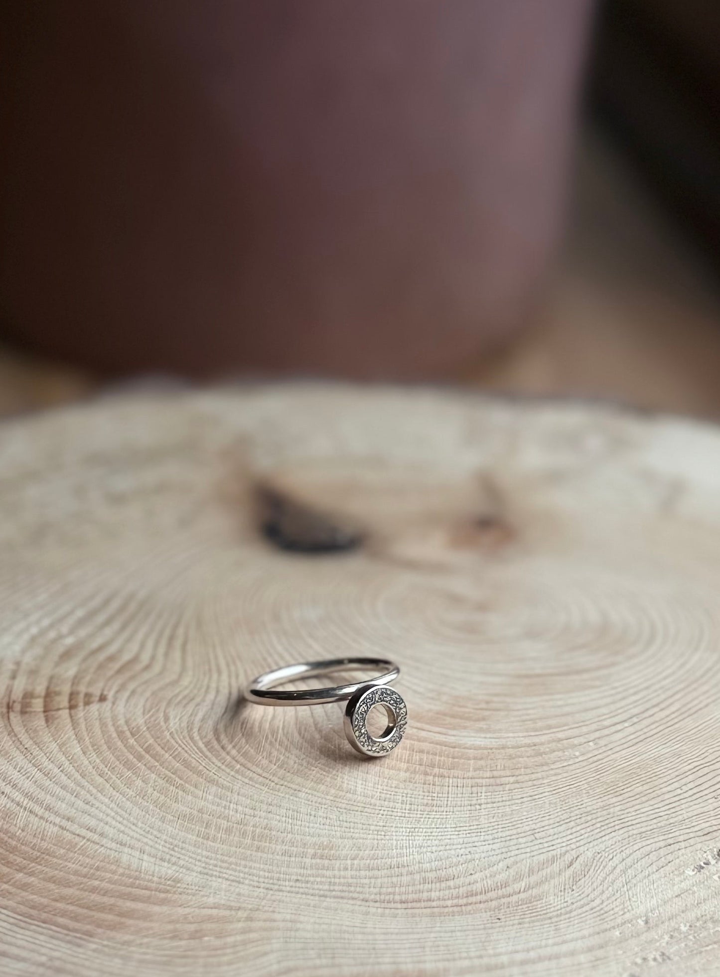 Silver ring band with donut on wooden block