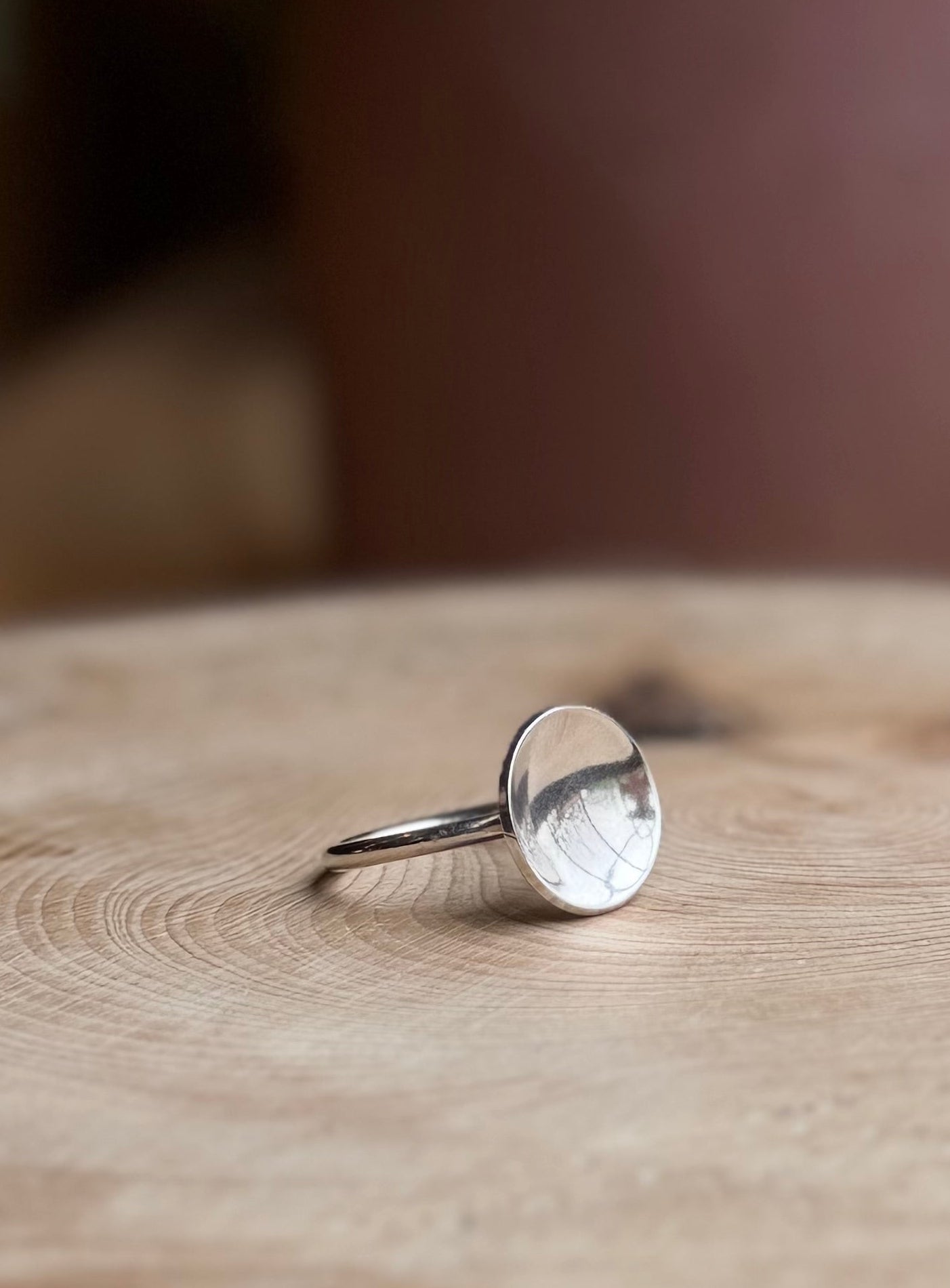 Silver slim band with polished dome resting on wood