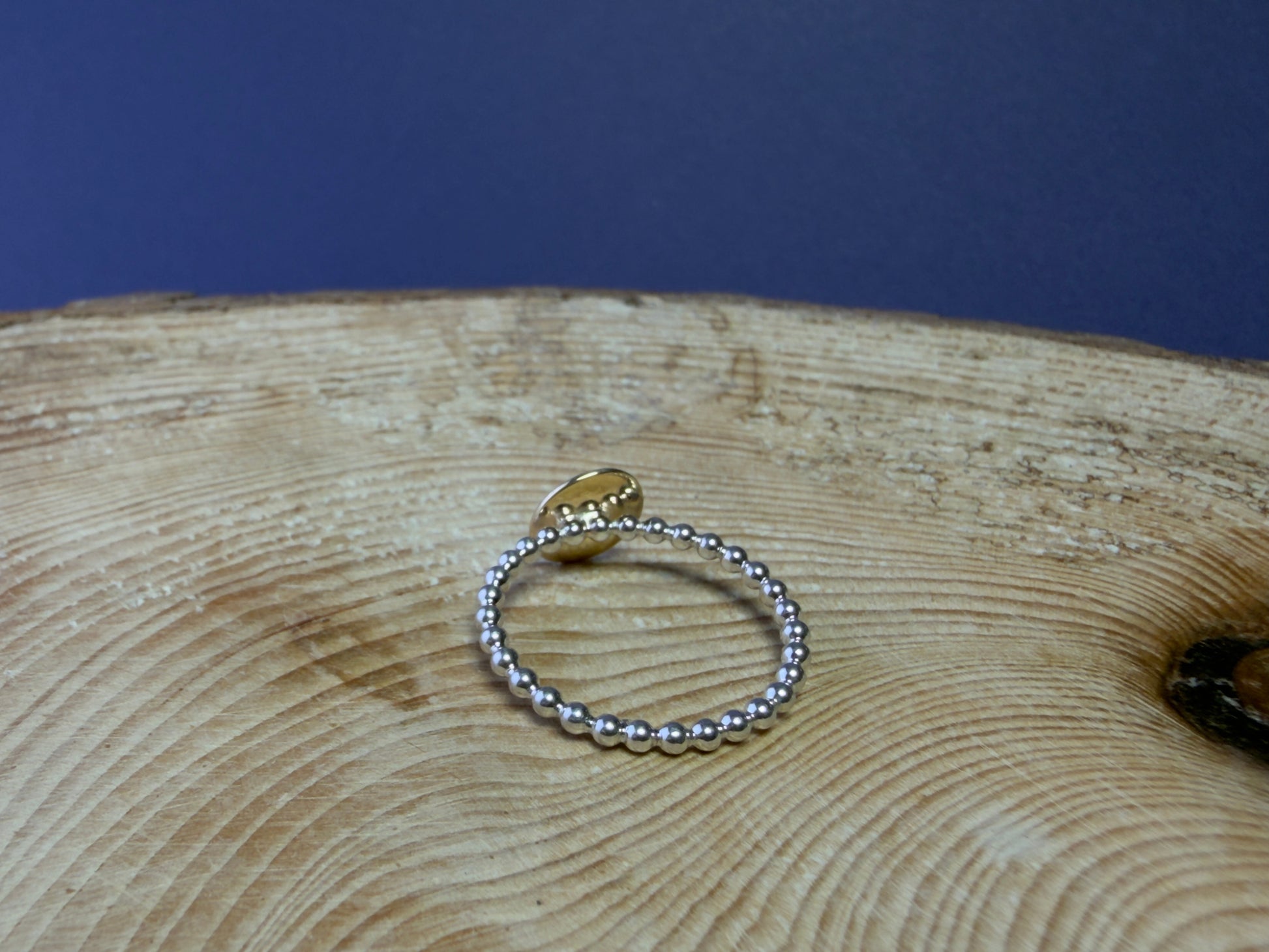 Gold and silver ring, on a wooden surface with a blue background.