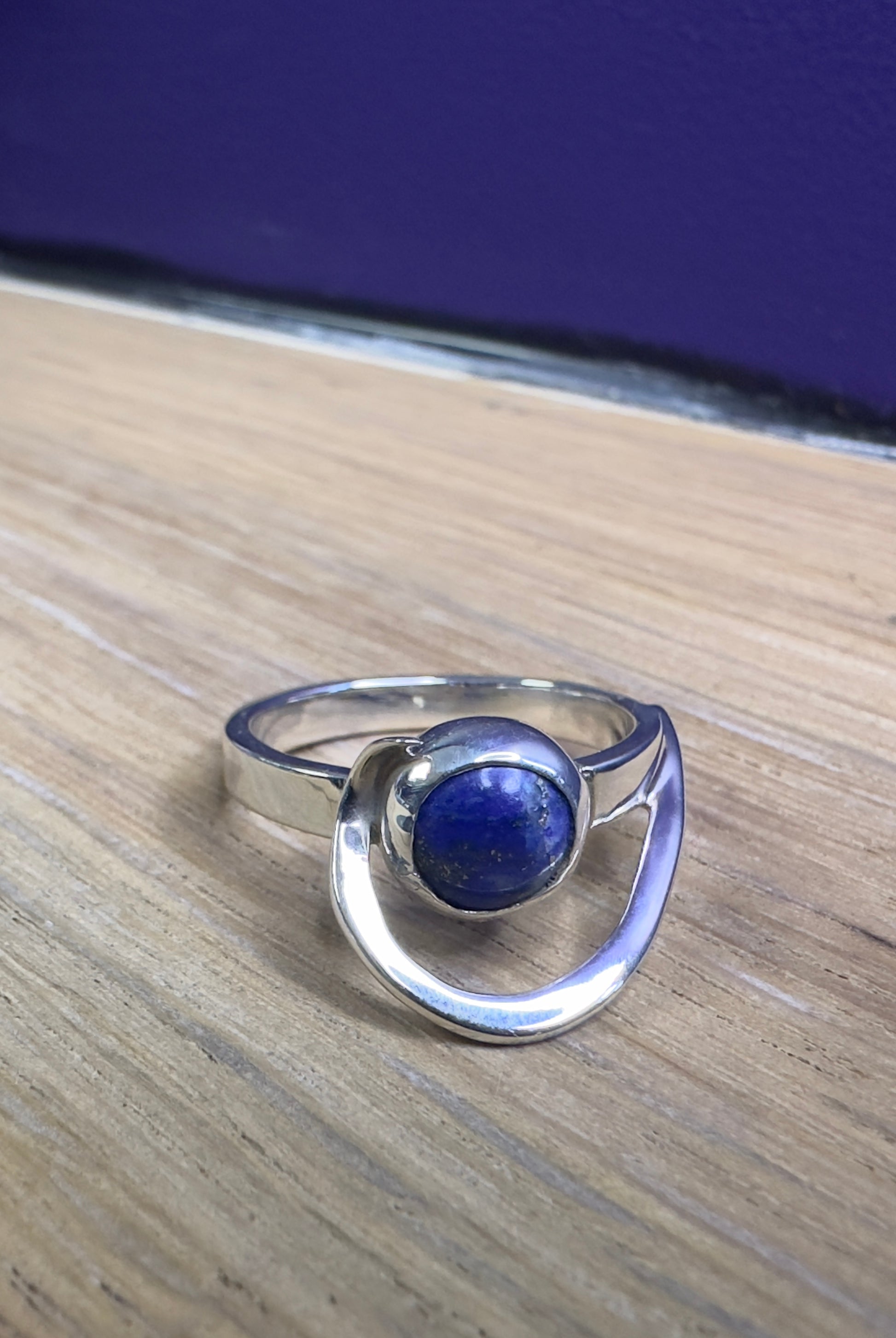 Silver ring with a blue stone on a wooden surface