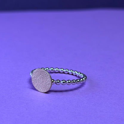 Silver ring with a round 9ct yellow disc on a purple background