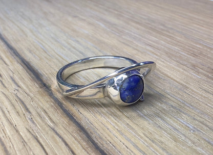 Silver ring with a blue stone on a wooden surface