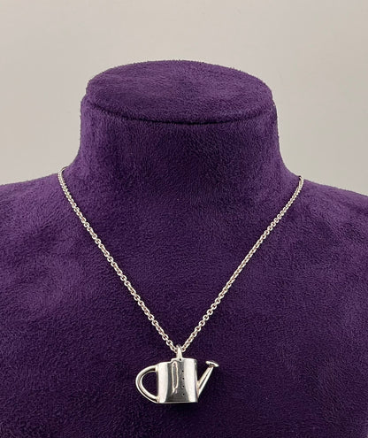 Watering can pendant on a chain displayed on a purple mannequin bust.