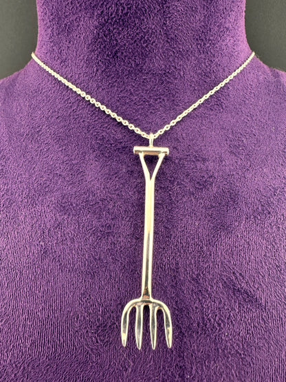 Silver garden fork pendant on a chain against a purple background