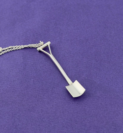Silver spade shaped pendant on a chain against a purple background