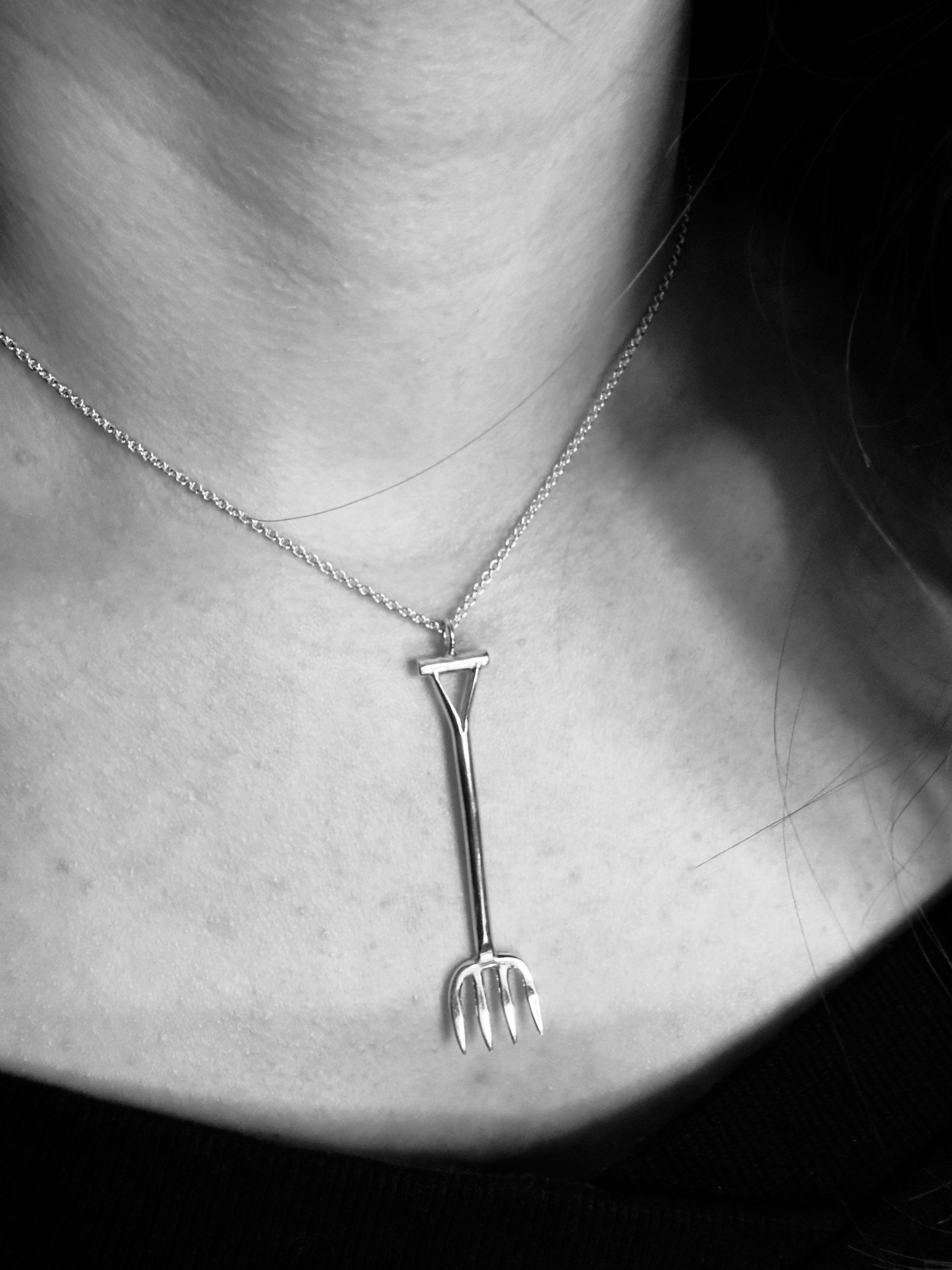 Silver necklace with a unique pendant worn by a person