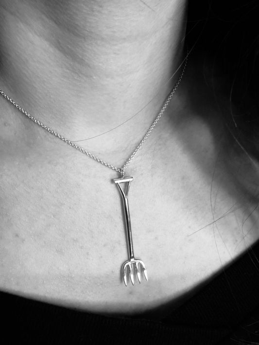 Silver necklace with a unique pendant worn by a person