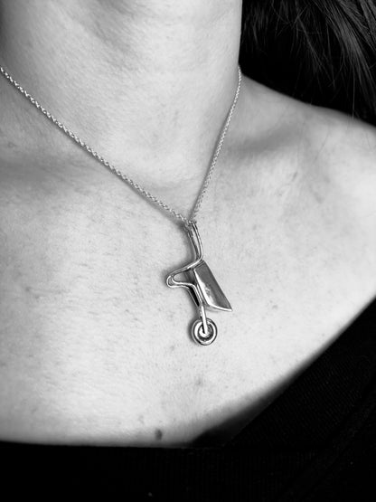 Silver wheelbarrow necklace with a unique pendant worn by a person