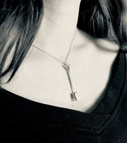 Silver necklace with a unique pendant worn by a person