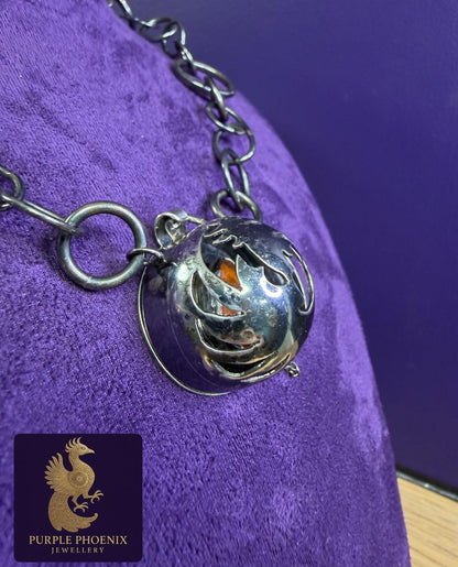 Silver necklace with a pendant on a purple textured surface, branded 'Purple Phoenix Jewellery'.