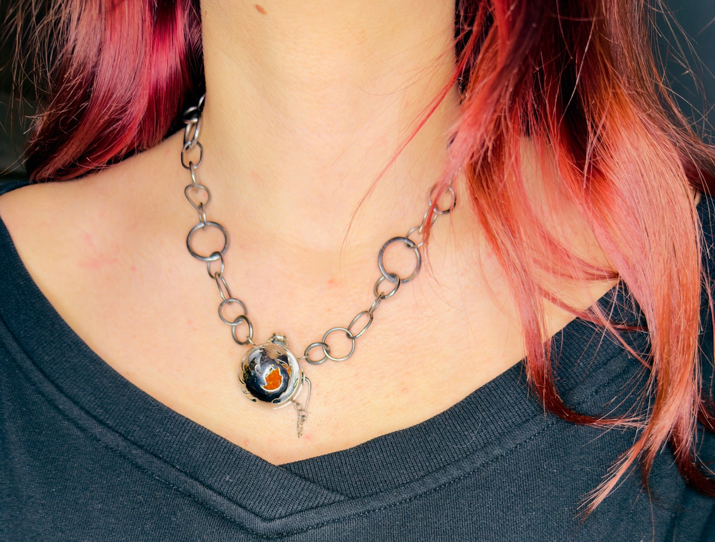 Necklace with a pendant worn by a person with pink hair