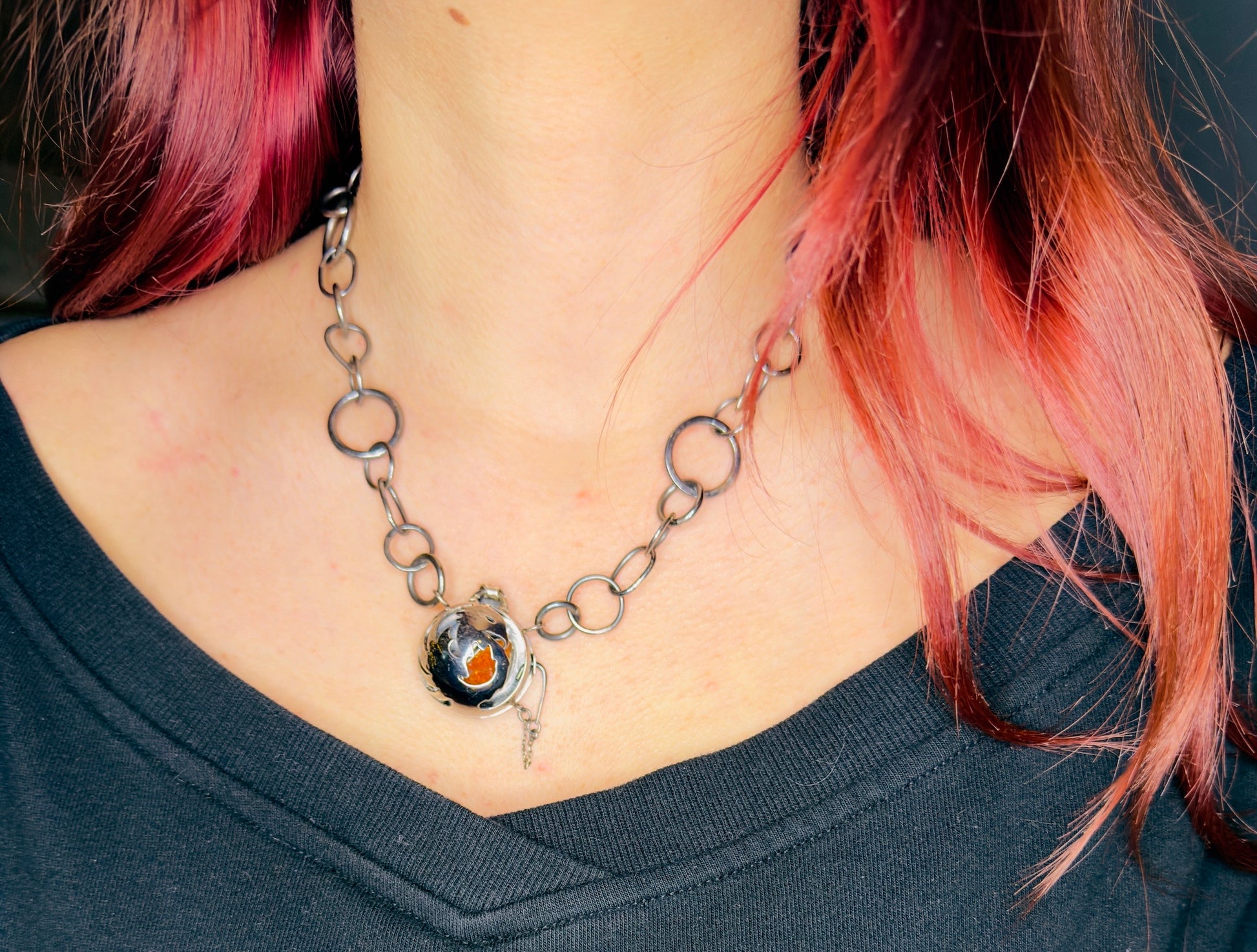 Necklace with a pendant worn by a person with pink hair