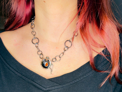Necklace with a pendant worn by a person with pink hair