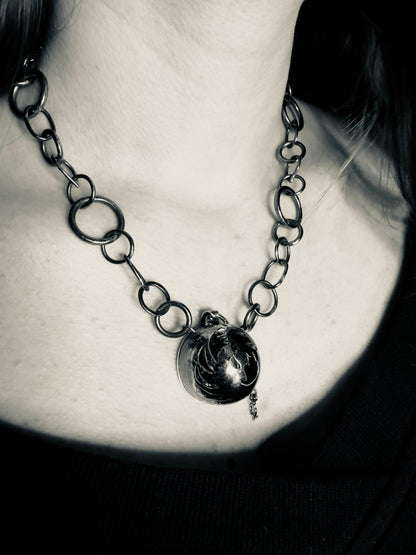 Close-up of a chain necklace with a pendant on a person's neck.