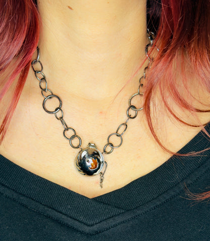 Necklace with a unique pendant worn by a person with pink hair.