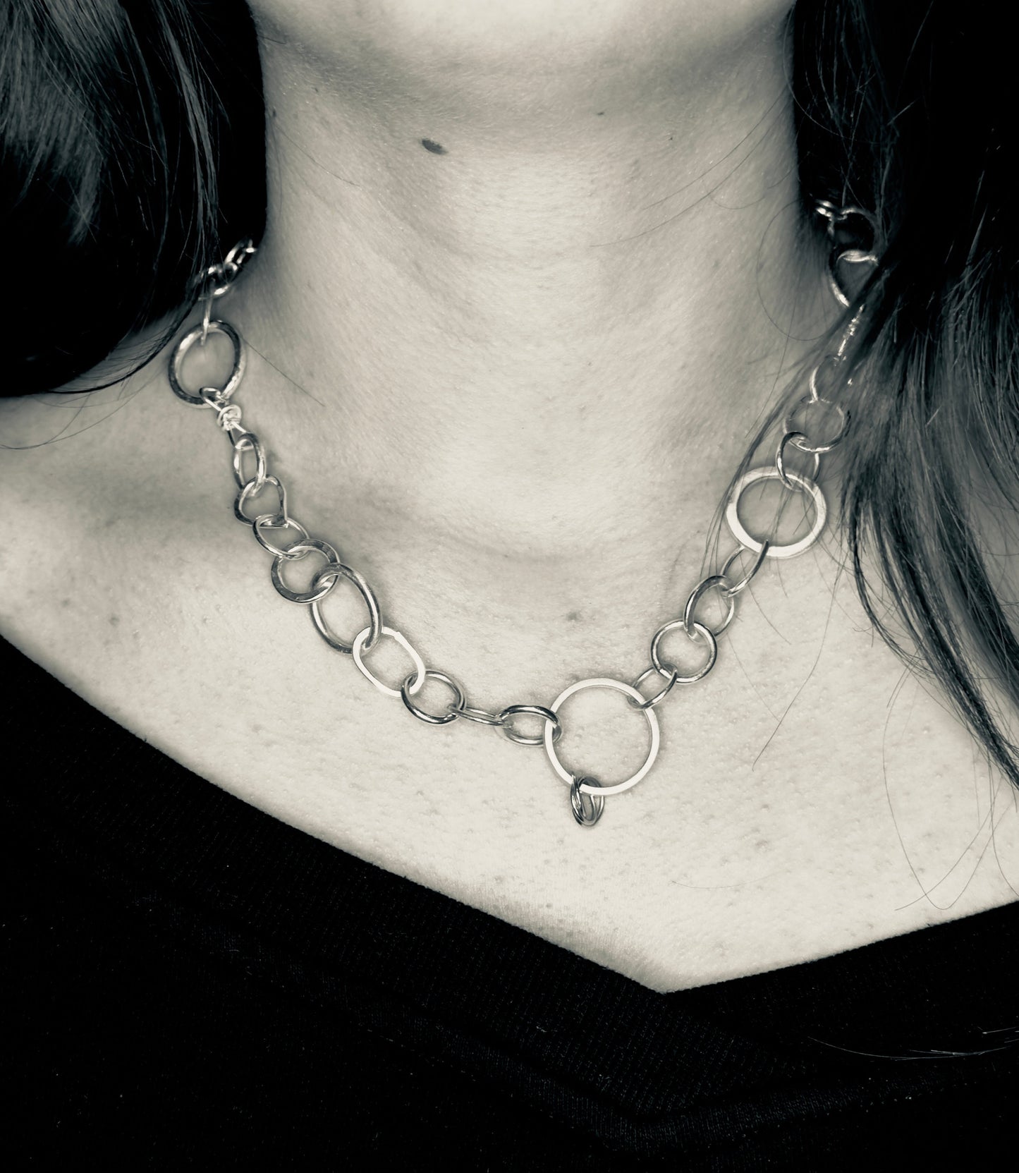 Close-up of a person wearing a chain necklace with a blurred background