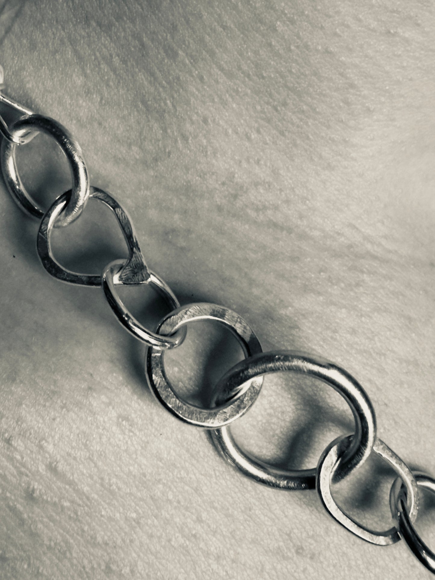 Close-up of a silver chain on a textured gray background