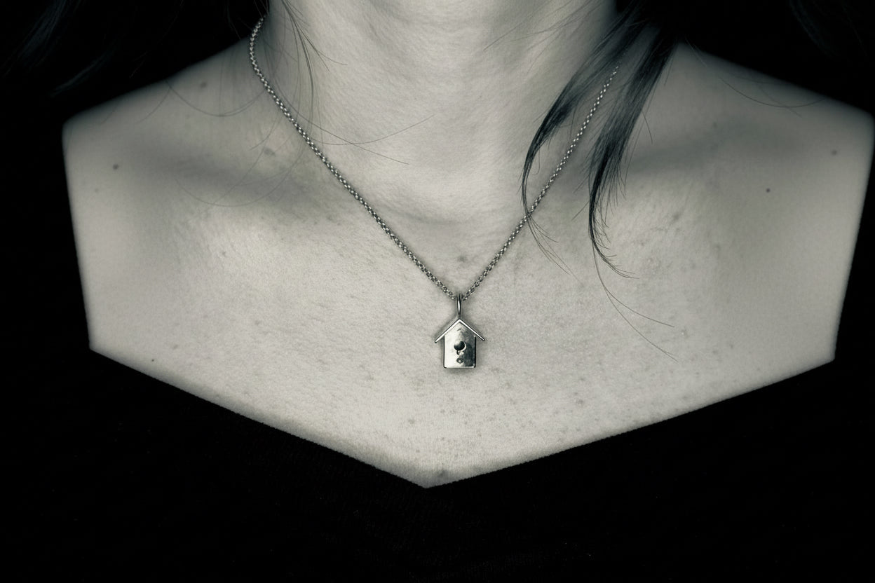 Necklace with a pendant featuring a birdhouse on a black background