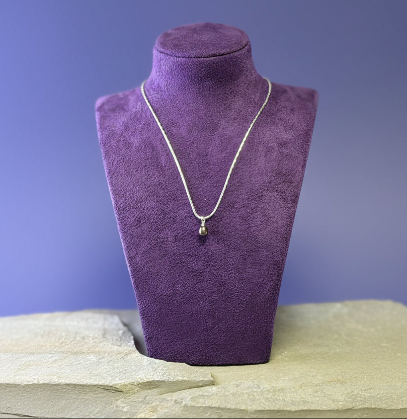 Pearl drop necklace on bust with slate background
