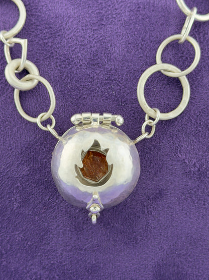Silver necklace with a round pendant on a purple background