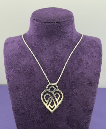 Necklace with a heart-shaped pendant on a purple mannequin bust.