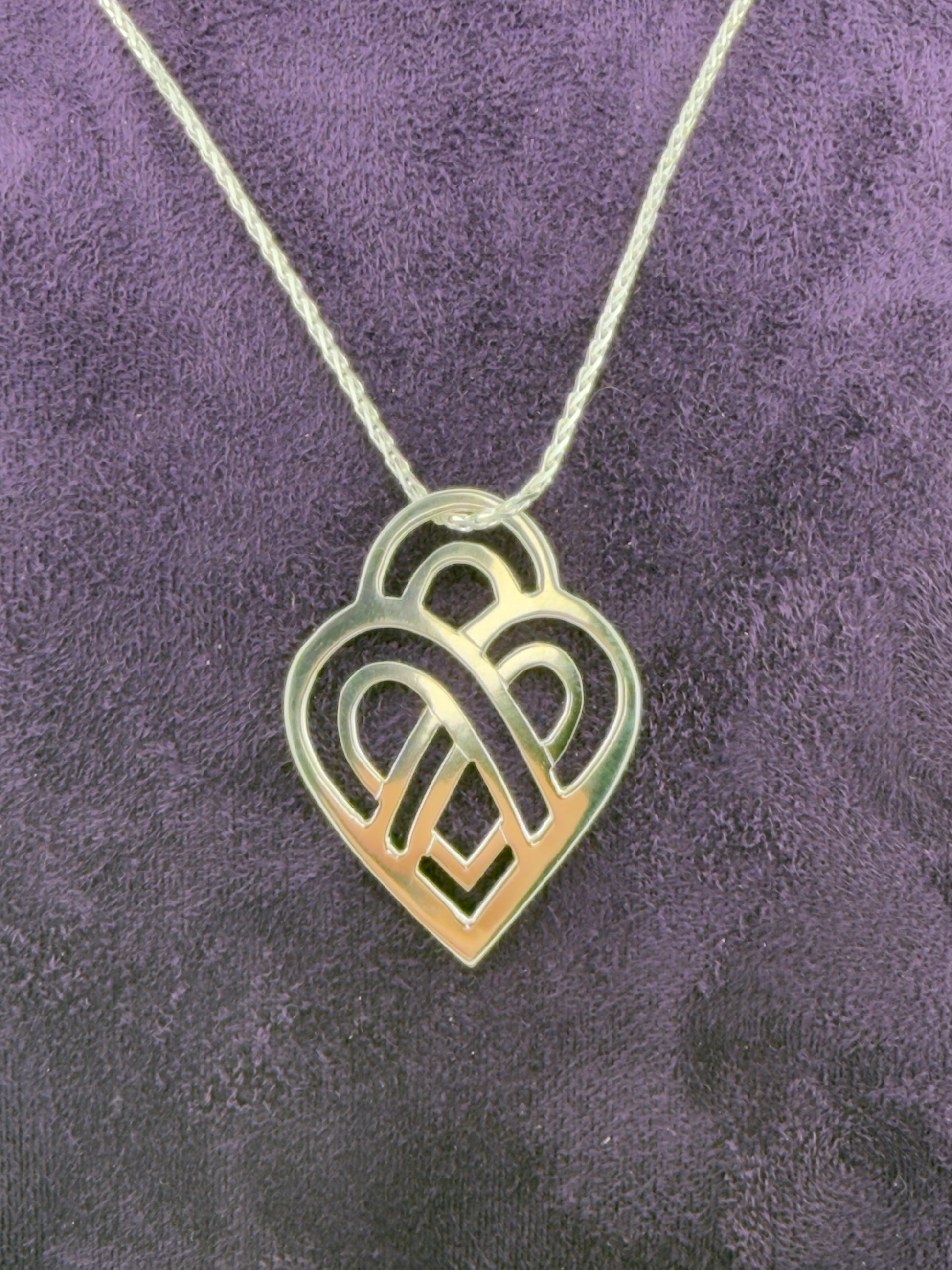 Heart-shaped pendant necklace on a textured purple background