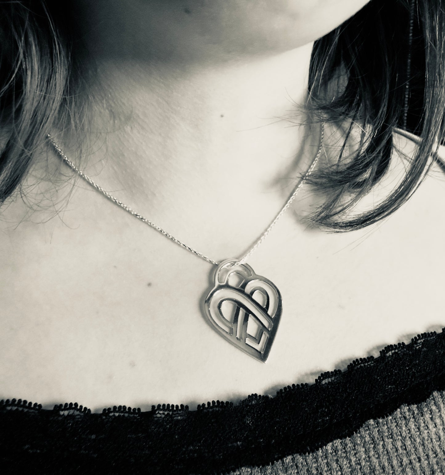 Person wearing a necklace with a heart-shaped pendant