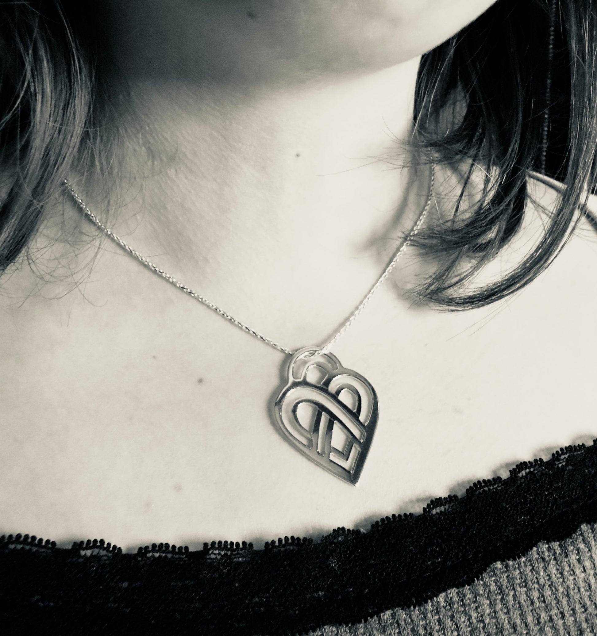 Person wearing a necklace with a heart-shaped pendant