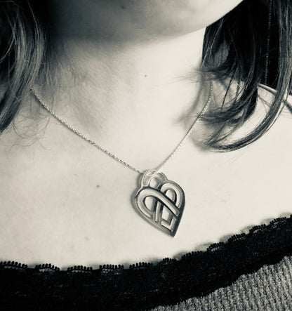 Person wearing a necklace with a heart-shaped pendant