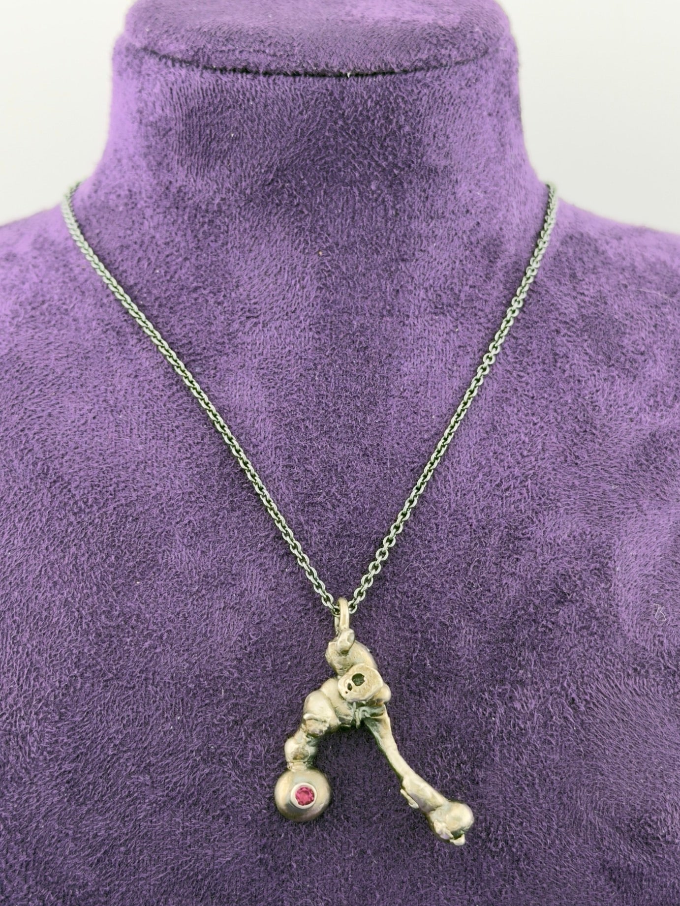 Necklace with a unique pendant on a purple mannequin