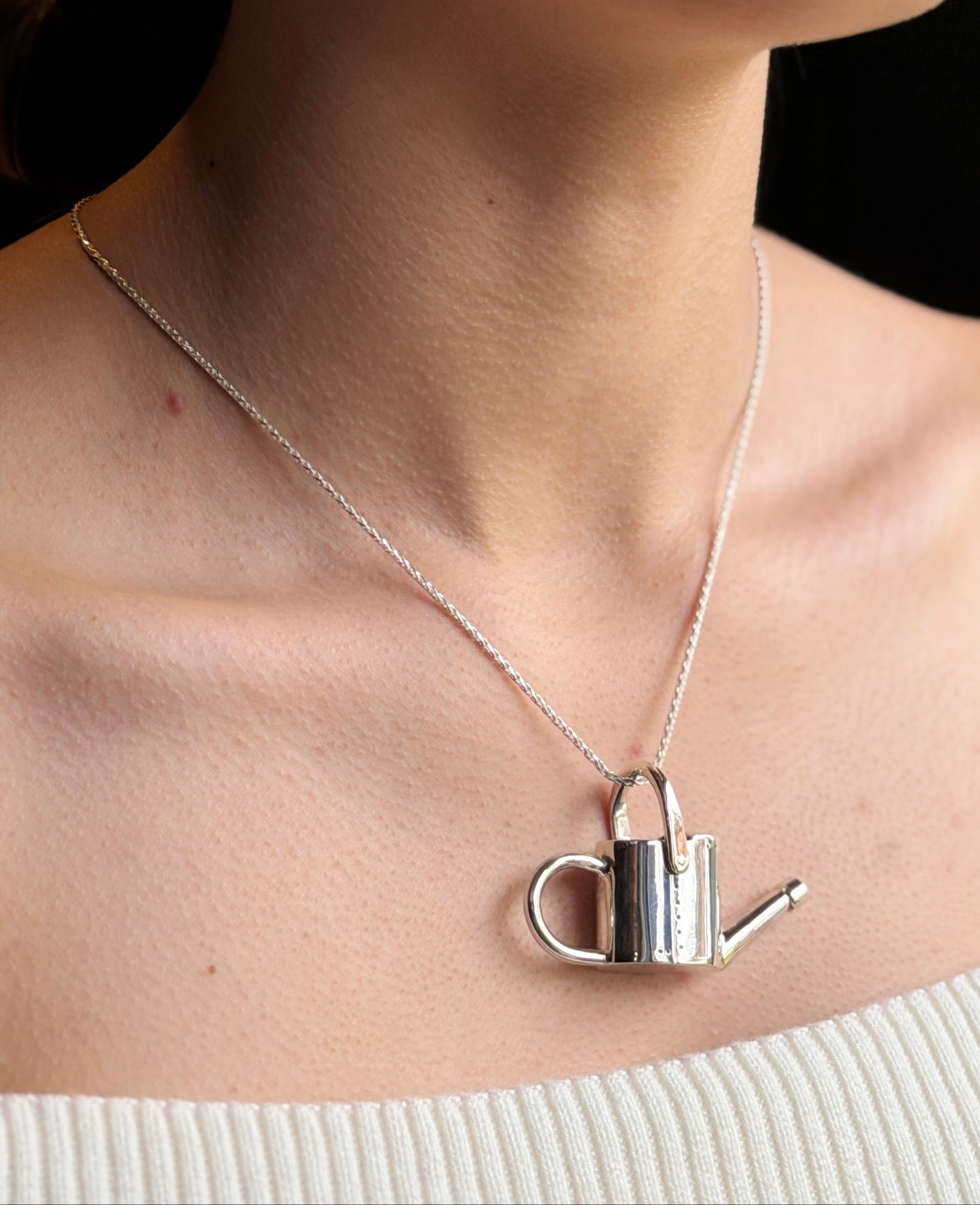 Watering can necklace on model
