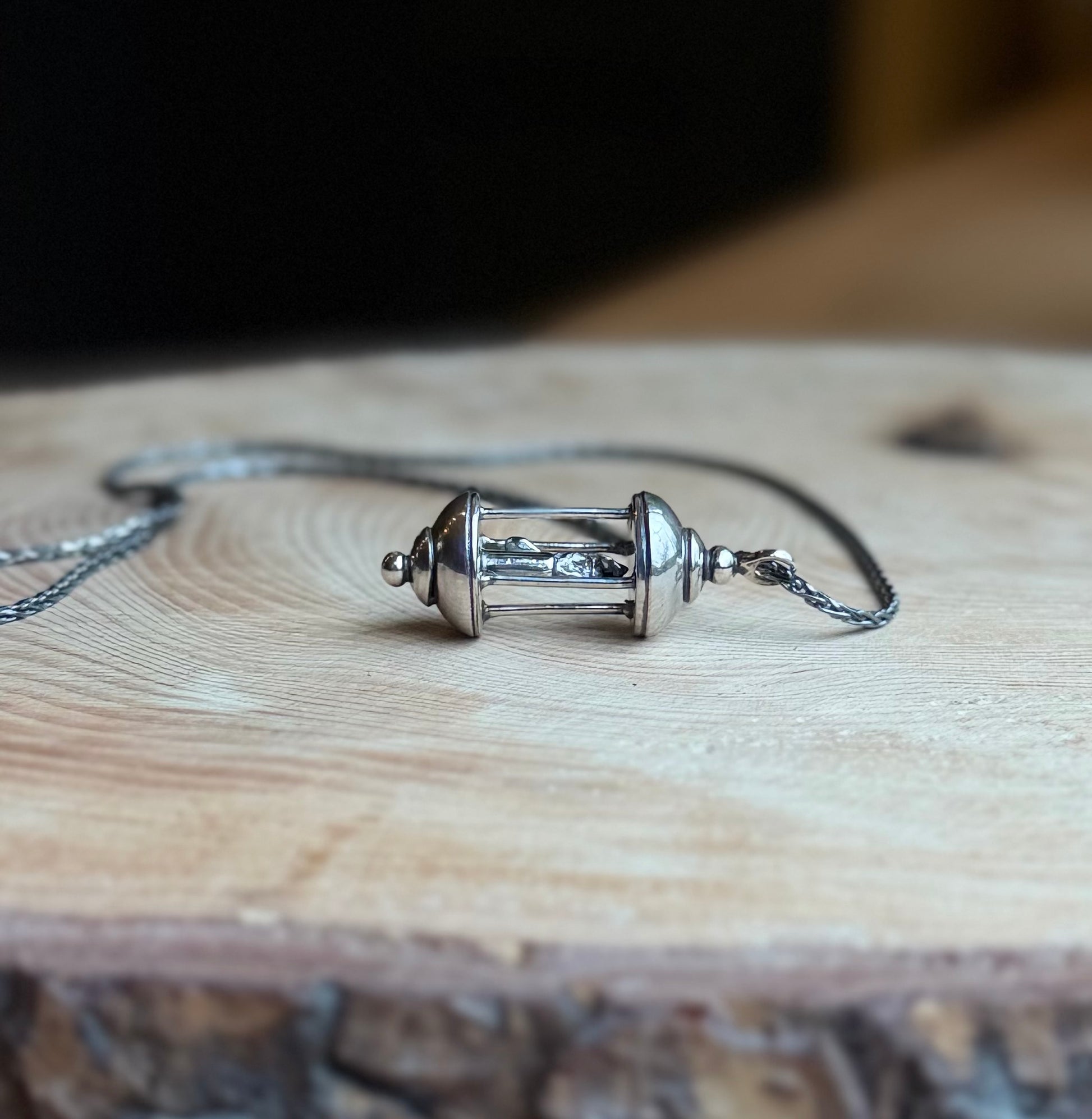 Sterling Silver Lantern pendant resting on wood