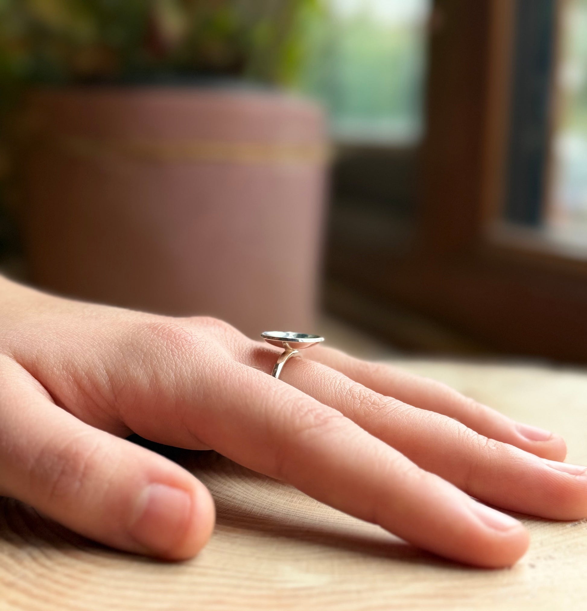 Silver slim ring band with polished dome on hand resting on wood