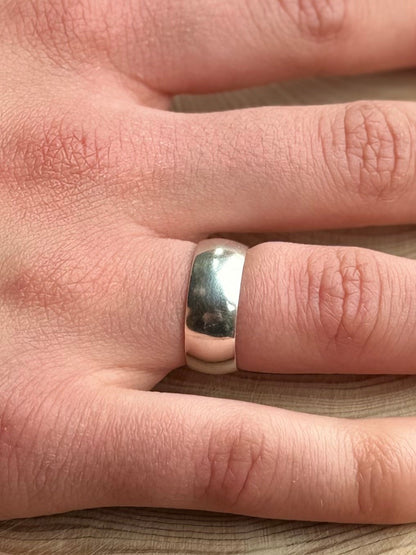 Wide silver ring band,D-shaped profile, on hand resting on wood