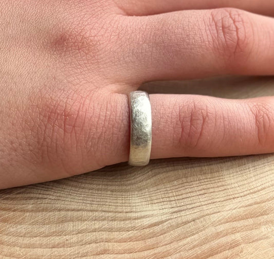 5mm wide hammered satin finish band on hand resting on wood