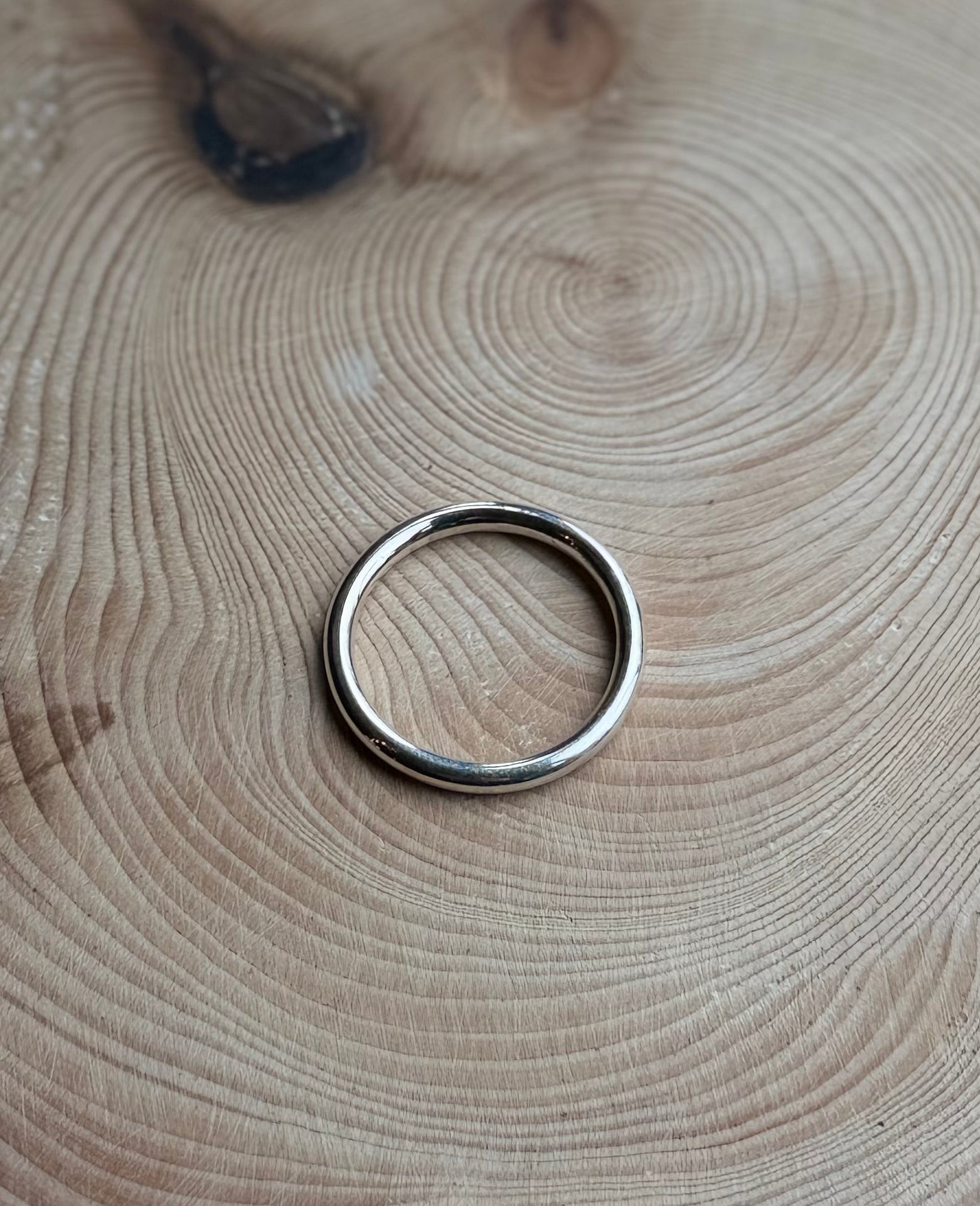 Silver round profile ring, polished, on wood
