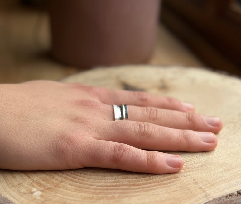 Hammered spinner ring band on hand resting on wood