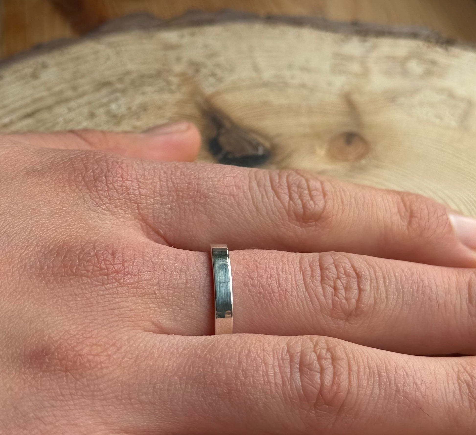 Flat ring band on hand placed on wood