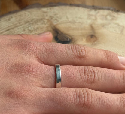 Flat ring band on hand placed on wood
