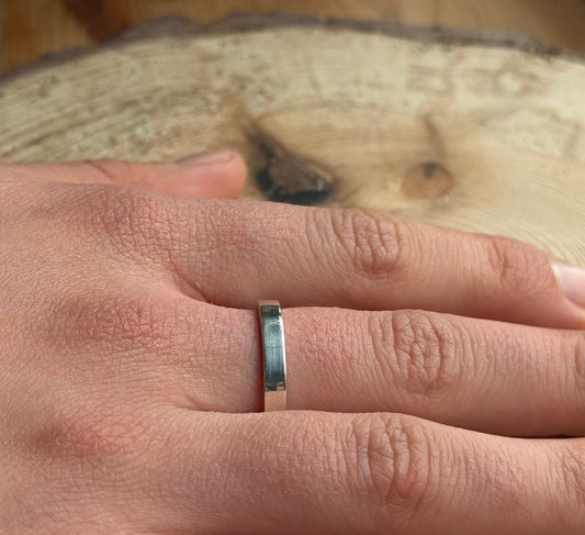 Flat ring band on hand placed on wood