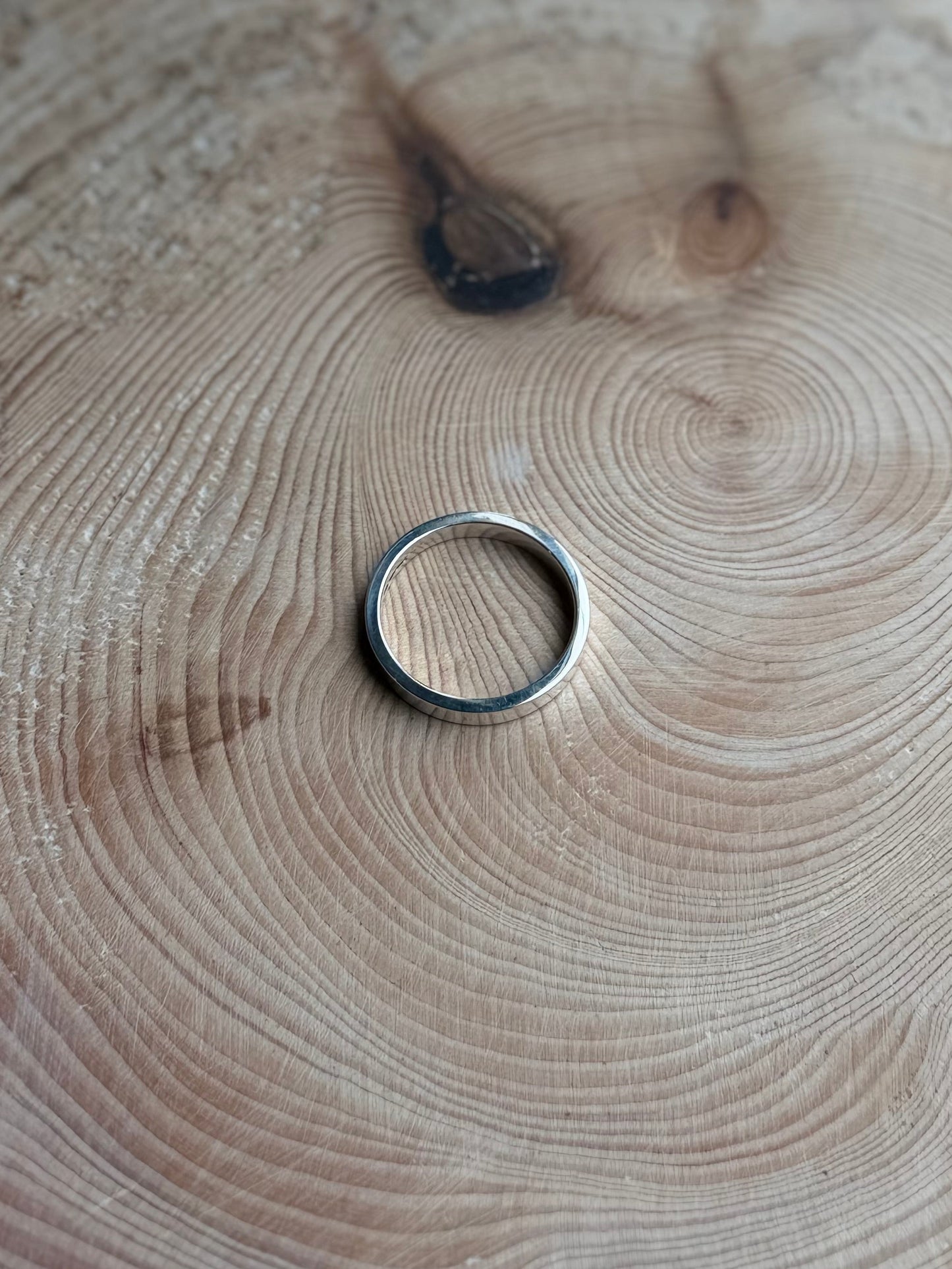 Flat ring made from silver on a wooden background