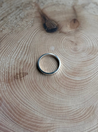 Flat ring made from silver on a wooden background