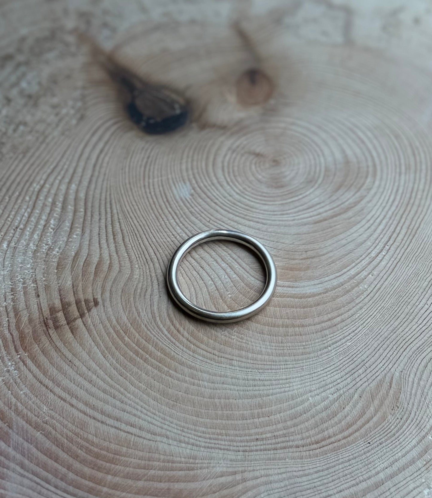 Silver round profile ring band, satin finish, on wood