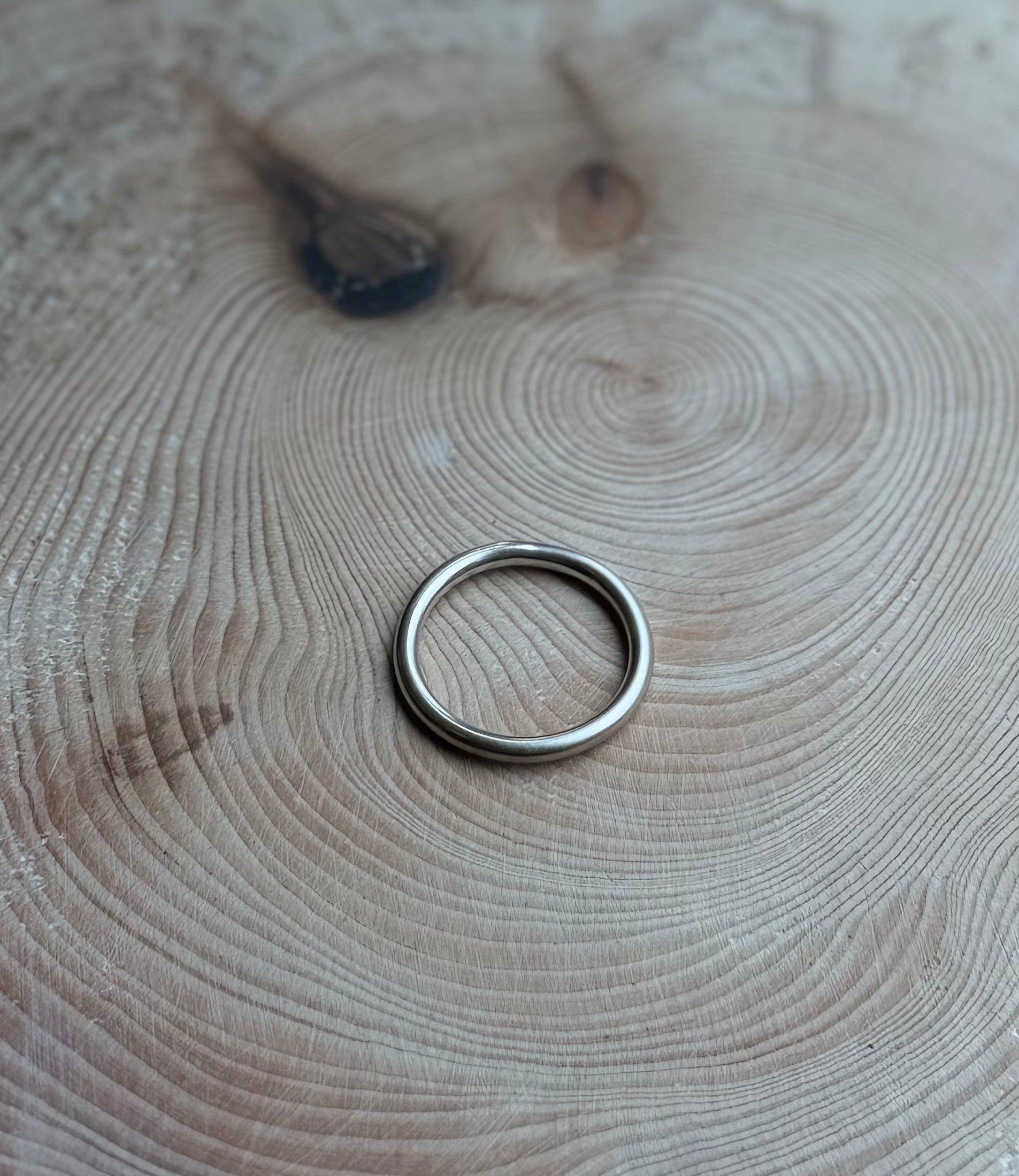 Silver round profile ring band, satin finish, on wood