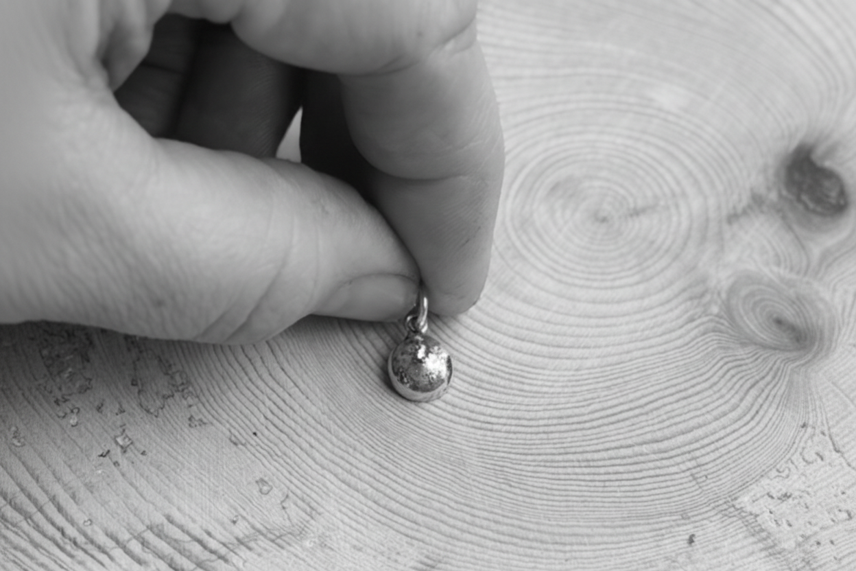 Black and white image of hand holding the TTMAB charm

