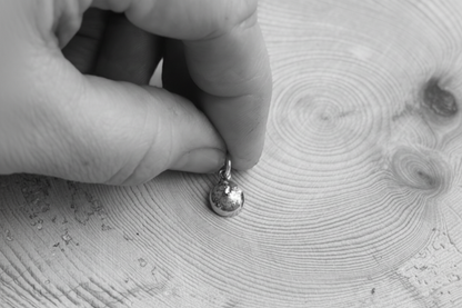 Black and white image of hand holding the TTMAB charm

