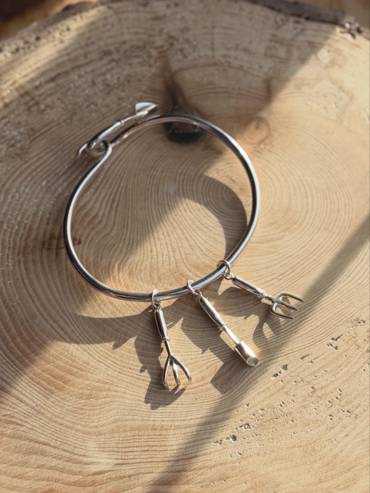Bangle with garden charms on, resting on wood