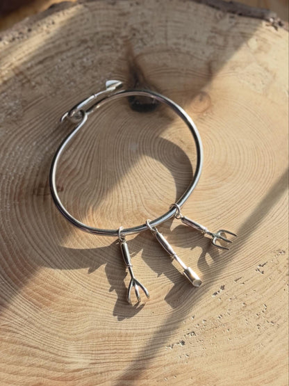 Bangle with garden charms on, resting on wood
