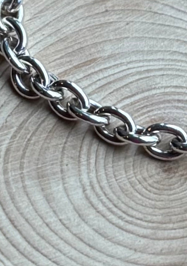 Section of silver  belcher chain on wood