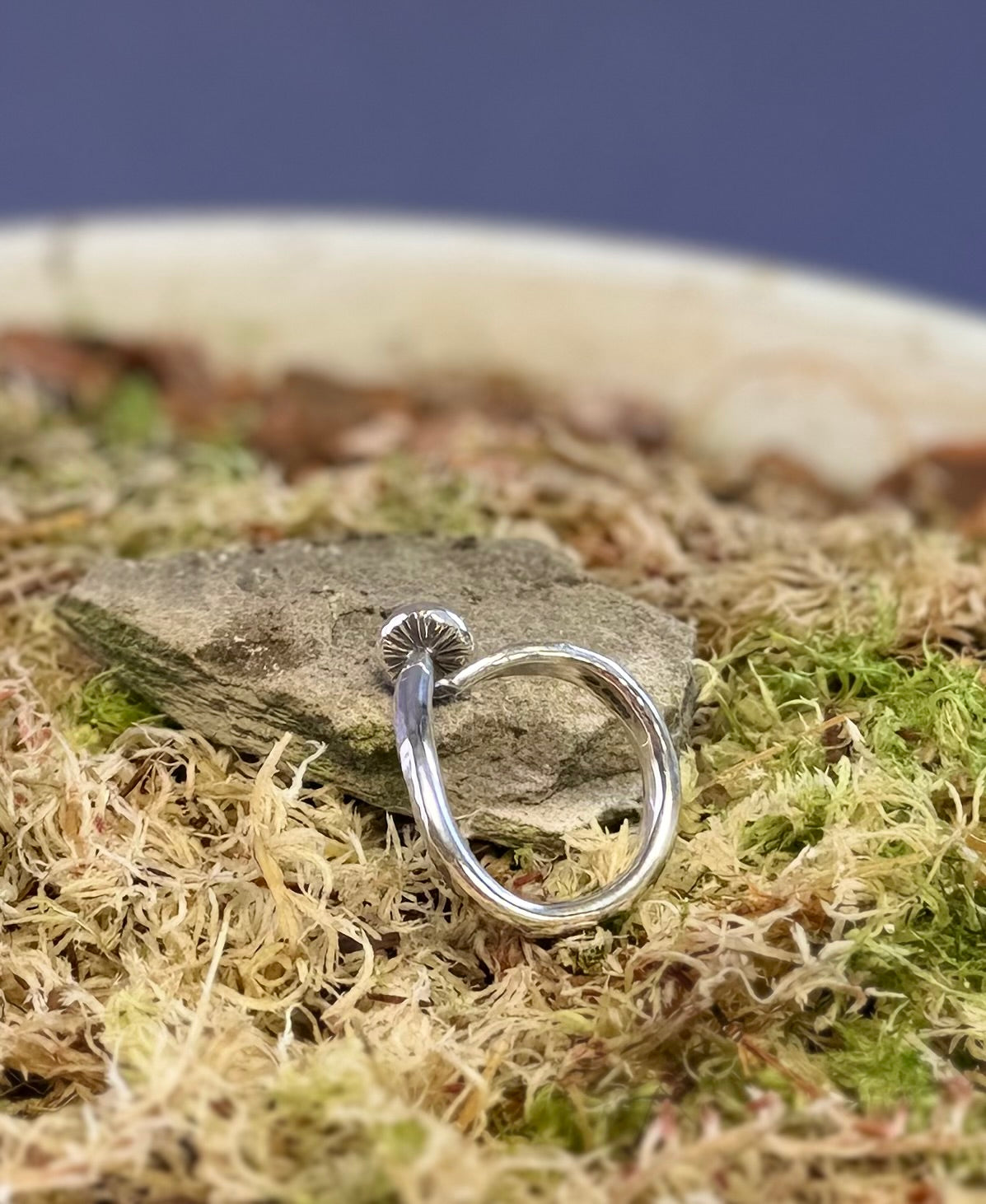 Silver ring with a mushroom design on a stone and moss background